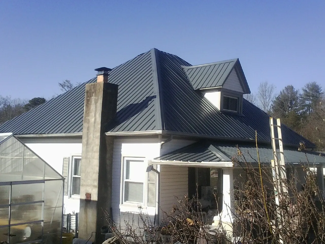 Dark blue standing seam metal roof on a white farmhouse with dormer — Slate & Tile Roof Repair by Roofing Brothers in Pompton Plains