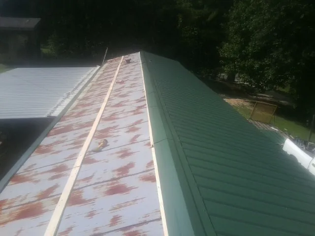 Old rusted panels beside newly installed green metal roofing — Wind Damage Roof Repair by Roofing Brothers in Pompton Plains