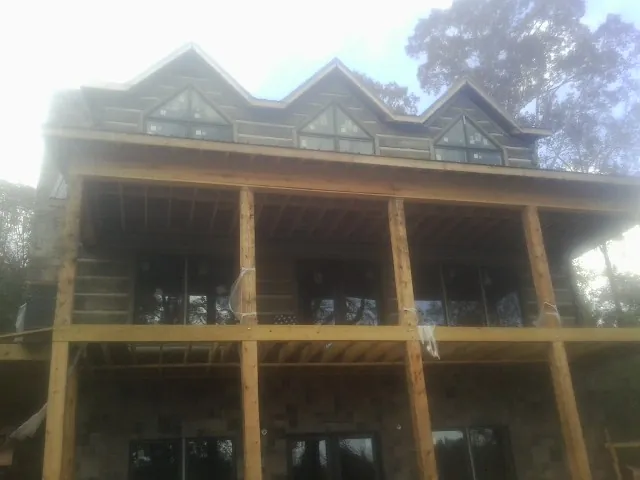 Dormers and porch framing on a large log home under construction — Roof Coating work by our crew in Pompton Plains