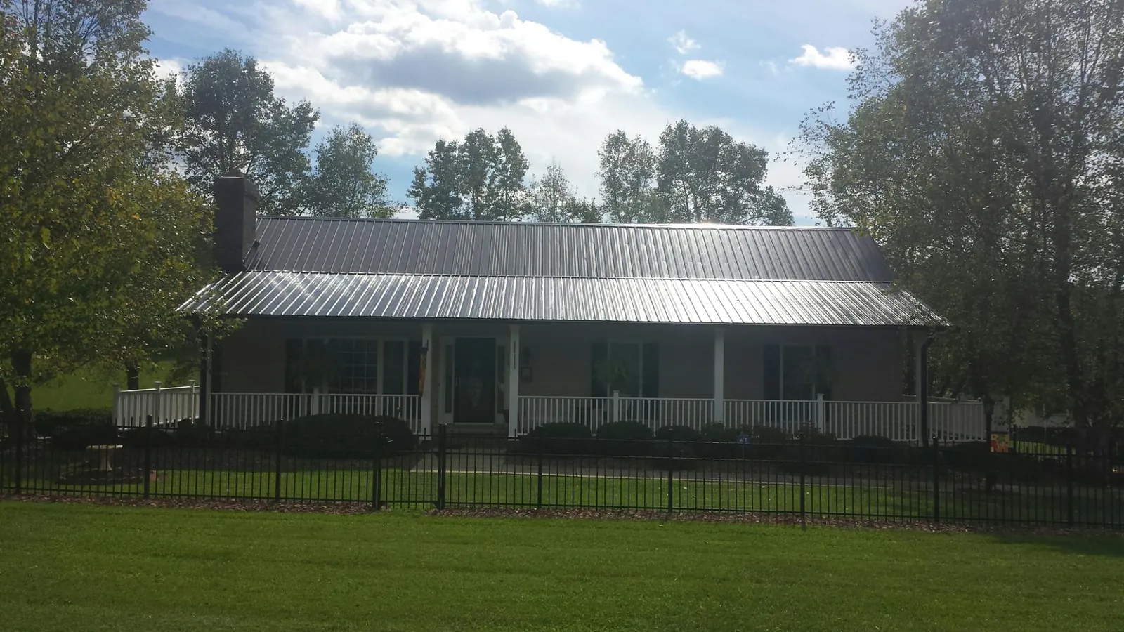 Gray metal roof on a brick ranch with a full width front porch — Gutter Guard Installation work by our crew in Pompton Plains