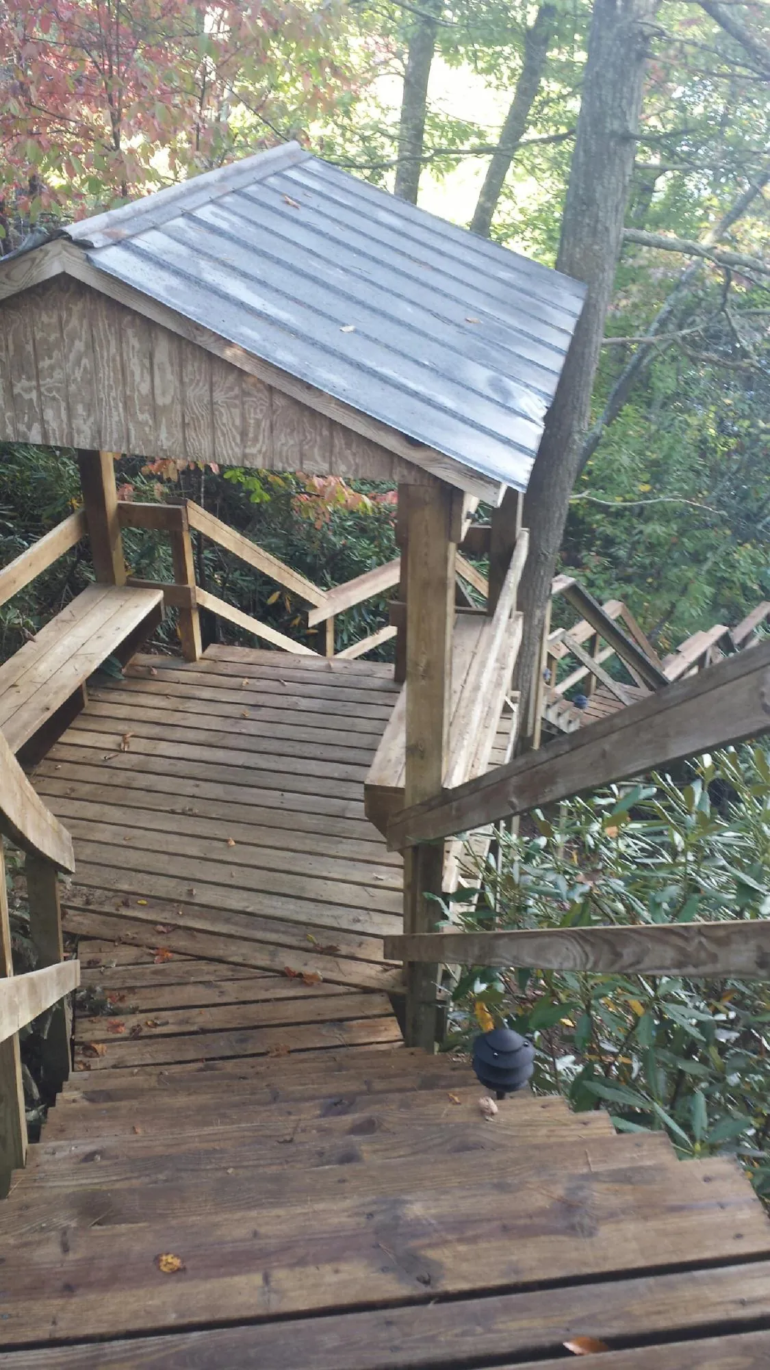 Metal roofed shelter over wooden steps on a wooded walkway — Skylight Repair & Installation work by our crew in Pompton Plains