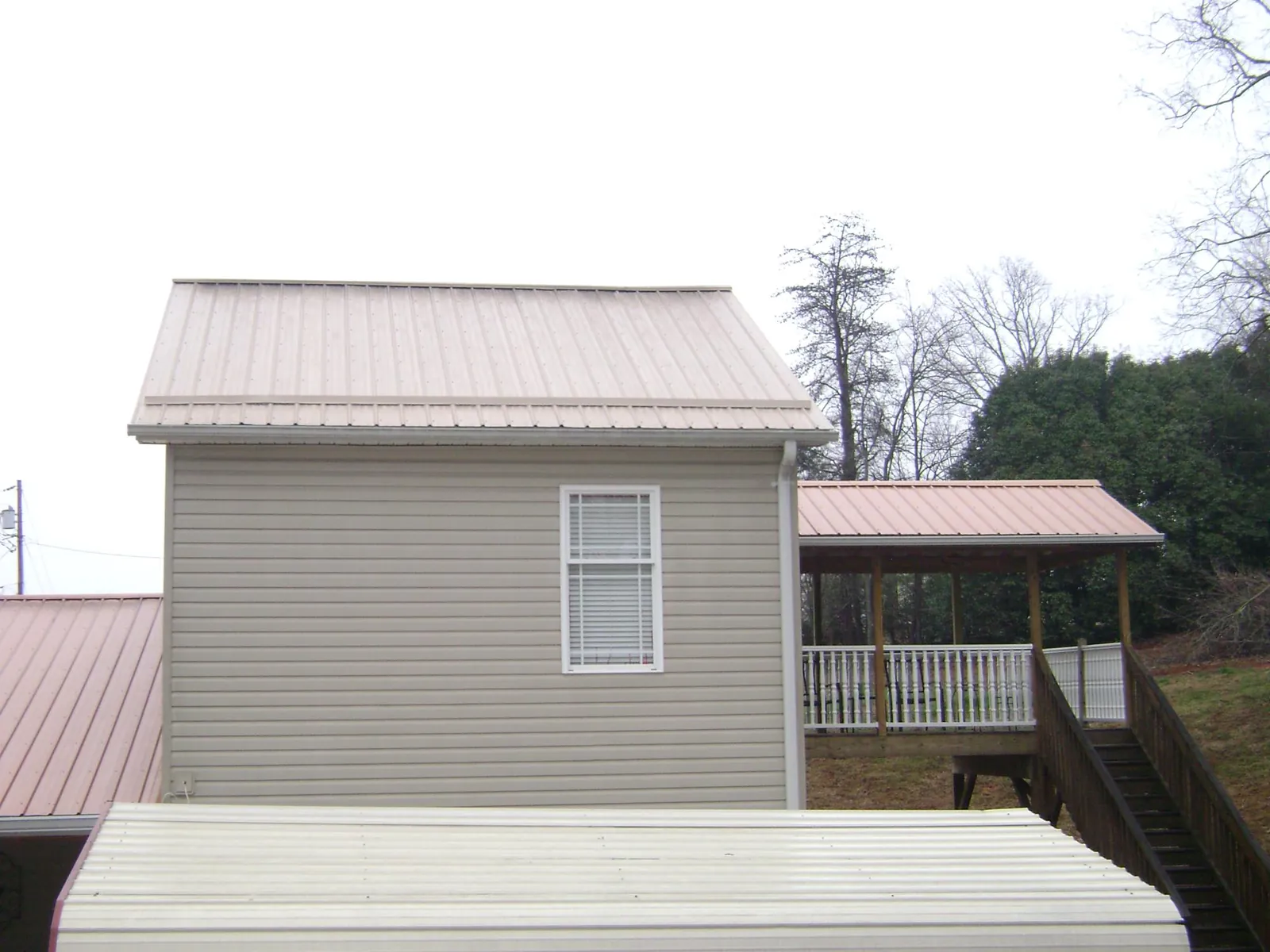 Tan metal roofs on a two story addition and attached porch, from a Roof Replacement job in Pompton Plains