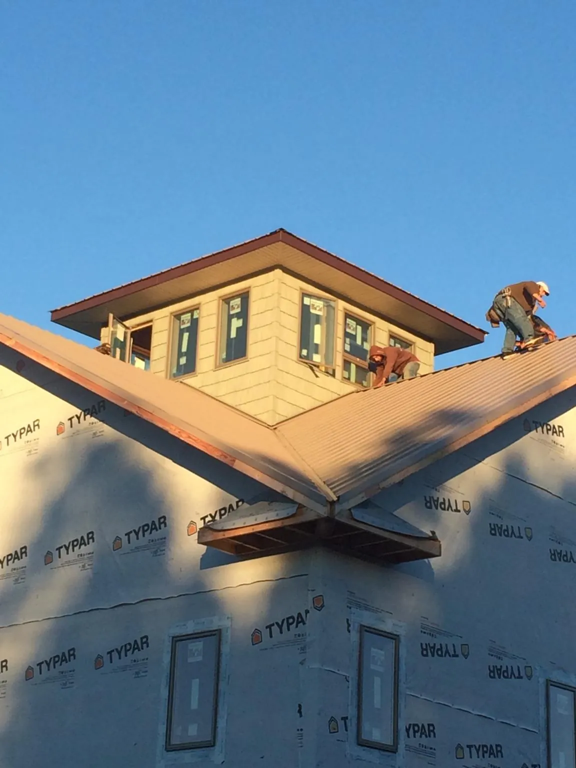 Roofers working around a rooftop cupola on a new metal roof at sunset — Roof Waterproofing in Pompton Plains by Roofing Brothers